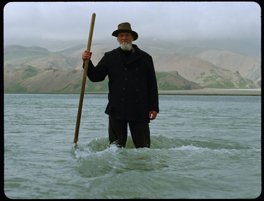 Pêcheur au chapeau et barbe grise dans l'eau de Godland, le film danois de Hlynur Palmason.