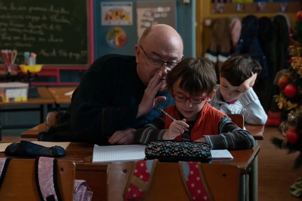 Michel Blanc chuchote à l'oreille d'un enfant à l'école dans Les Petites Victoires.