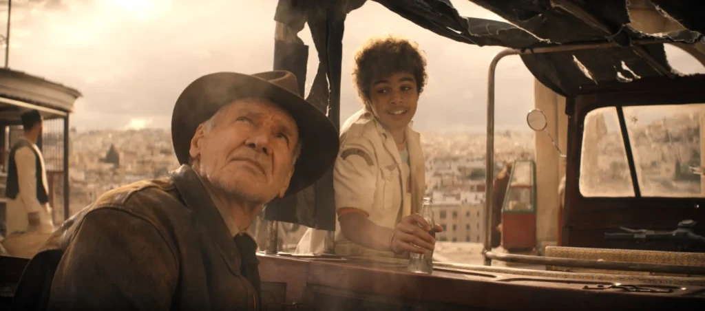 Harrison Ford regarde le ciel en Indiana Jones un enfant derrière lui.