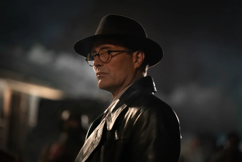 Mads Mikkelsen chapeau noir lunettes noires ciré noir dans Indiana Jones.