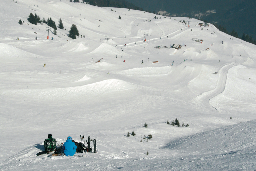 Vue sur les pistes des 7 Laux en Isère, deux personnes assises de dos.