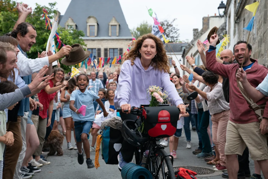 Julia Piaton à vélo acclamée par la foule dans Les Petites Victoires.