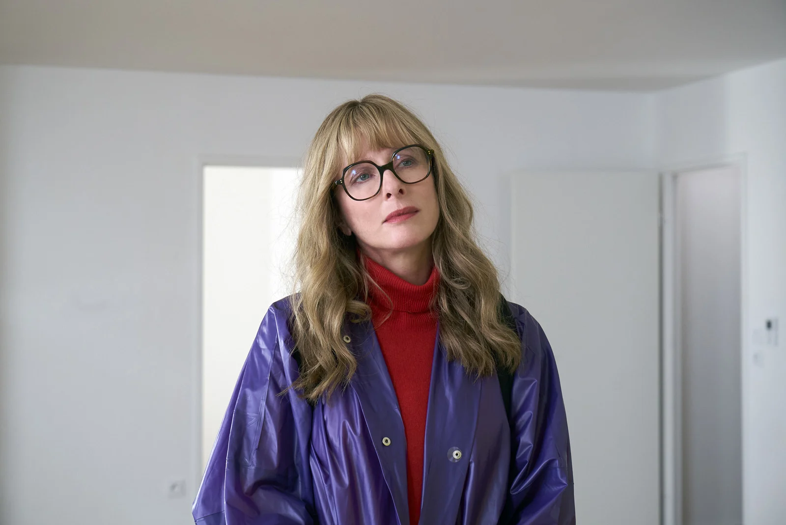 Karin Viard lunettes imper violet col roulé rouge.