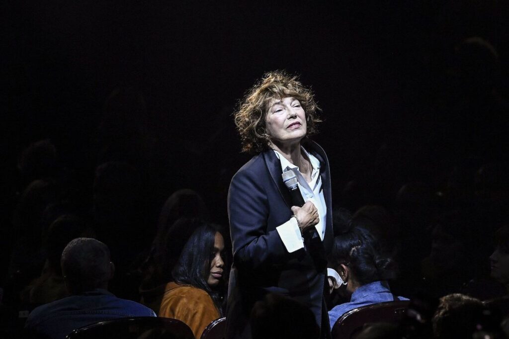 Jane Birkin costume micro au milieu du public assis Gainsbourg Symphonique.