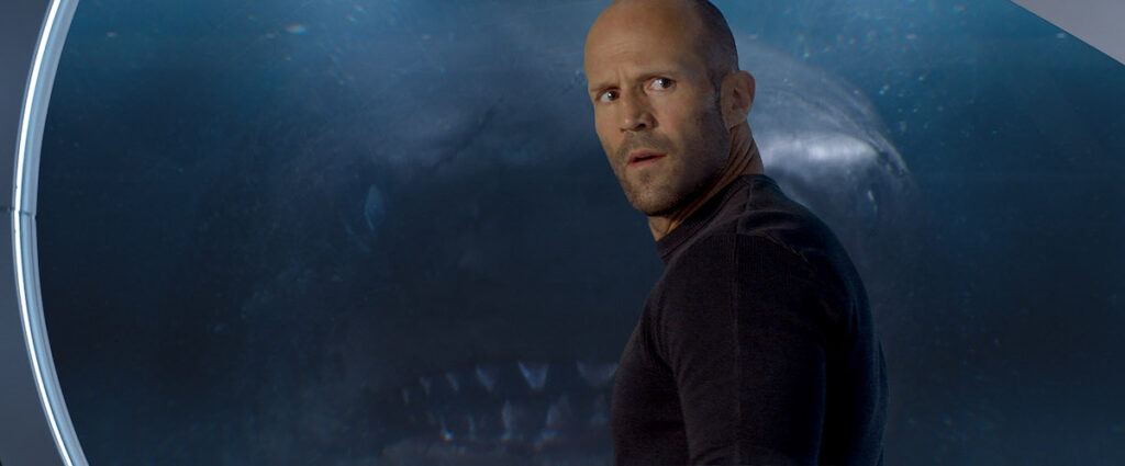 Jason Statham de profil requin derrière la vitre En eaux troubles.