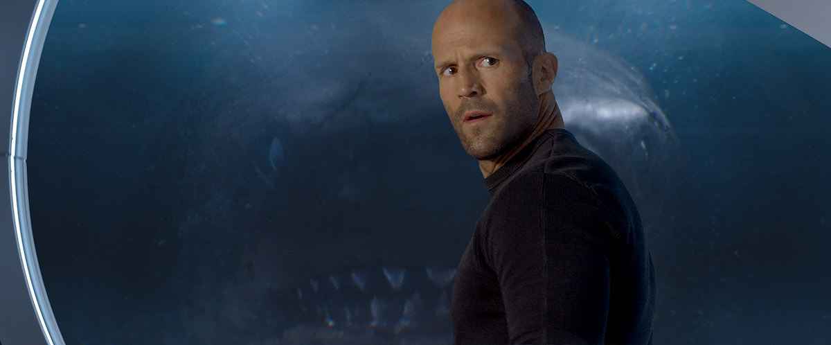 Jason Statham de profil requin derrière la vitre En eaux troubles.